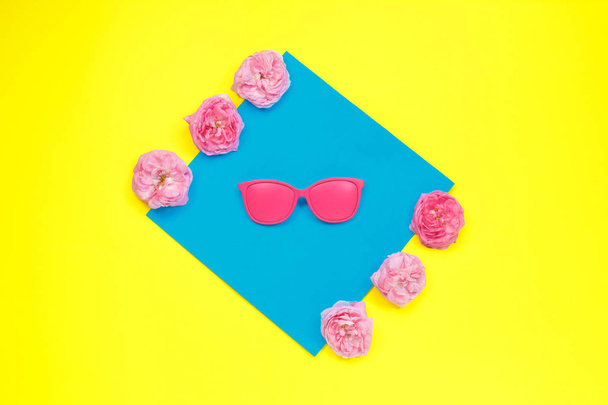 Gafas de sol de color rosa brillante y rosas rosadas en vibrante color negrita sobre fondo dual. concepto de moda. minimalismo. Plano laico, vista superior, concepto de verano
. - Foto, imagen