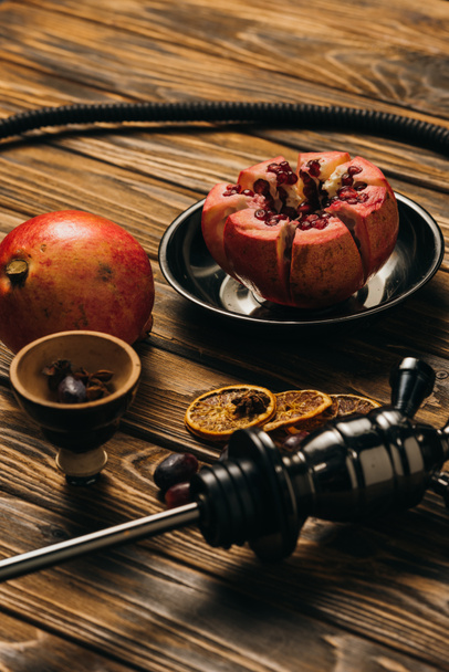 hookah, garnets and dried cut oranges on wooden surface - Foto, afbeelding