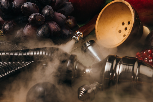 selective focus of fresh tasty grapes, garnet and hookah in smoke - Photo, Image