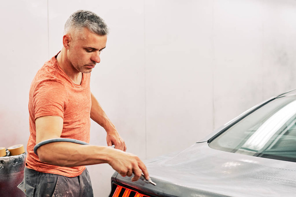 Ein Mechaniker bereitet ein Auto vor, um es zu lackieren - Foto, Bild