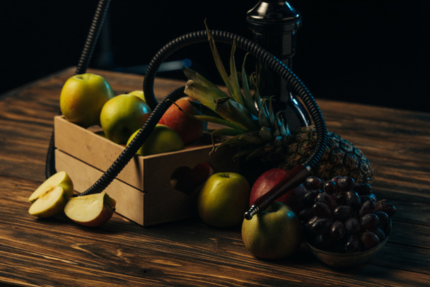 fresh tasty fruits and hookah on wooden surface isolated on black - Photo, Image