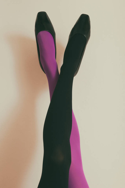Beautiful legs  of a woman in in different color tights and high heels up in front of wall.Toned photo - Foto, immagini
