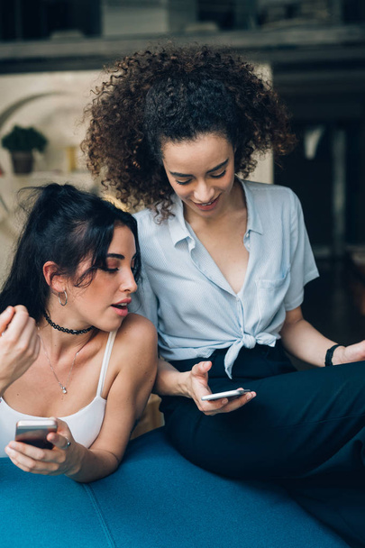 dvě mladé kavkazské ženy interagující s chytrým telefonem - Fotografie, Obrázek