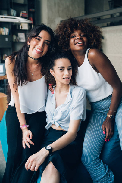 drie jonge multiraciale vrouwen poseren samen en op zoek camera - Foto, afbeelding