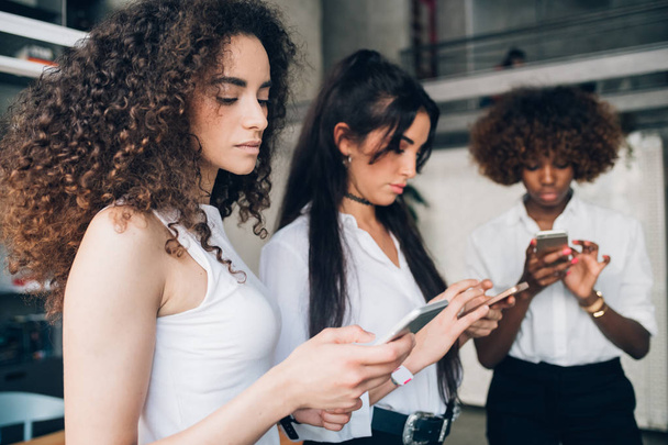 trois jeunes femmes d'affaires vérifiant et partageant des données avec un smartphone
 - Photo, image
