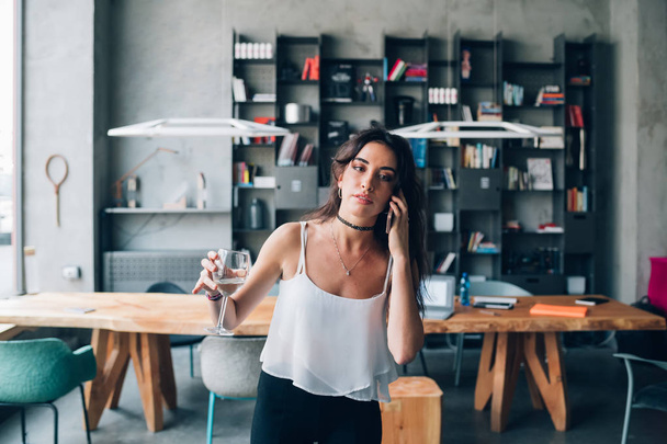 young caucasian woman drinking and having call in modern coworki - Foto, Imagen