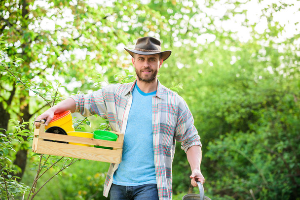 sexy farmer hold wooden box with pot. farming and agriculture cultivation. Garden equipment. Eco farm worker. Harvest. happy earth day. Eco living. ranch man in cowboy hat. Confident gardener - Foto, afbeelding