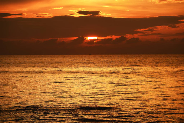 Le soleil levant et le ciel jaune doré sur la plage au bord de la mer tôt le matin
 - Photo, image