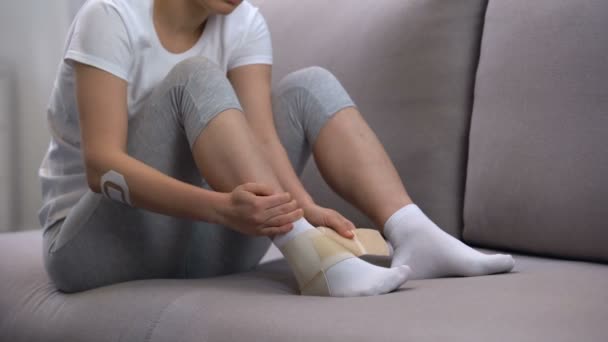Female applying two-strap ankle wrap, suffering foot edema after sport trauma - Filmagem, Vídeo