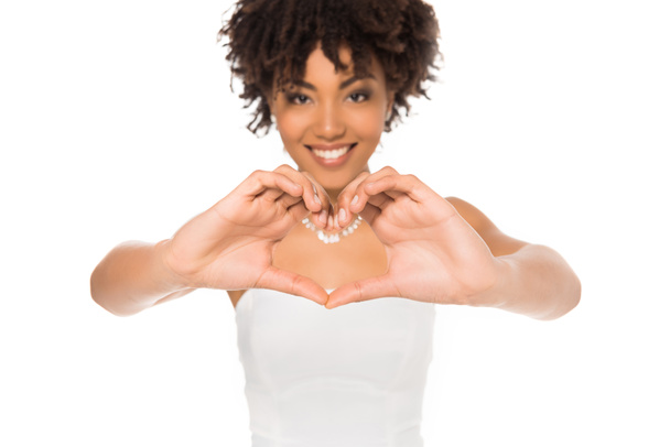 selective focus of happy and curly african american bride showing heart with hands isolated on white  - Photo, Image