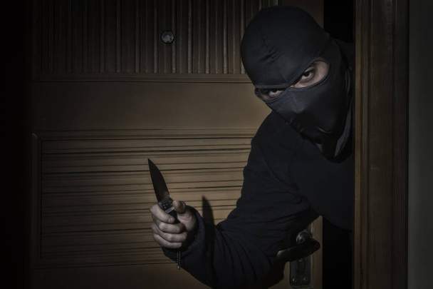 Ladrón con un cuchillo en la mano y un sombrero con una hendidura en el ojo
 - Foto, Imagen