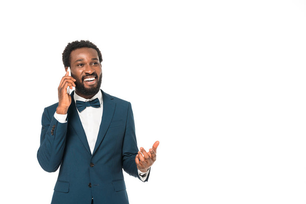 happy african american man in suit talking on smartphone isolated on white  - Valokuva, kuva