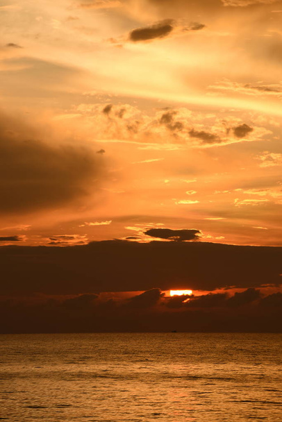 De opkomende zon en de goudgele hemel op het strand aan zee in de vroege ochtend - Foto, afbeelding