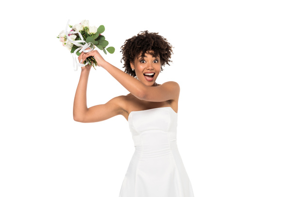  excited african american bride throwing bouquet and looking at camera isolated on white  - Photo, Image