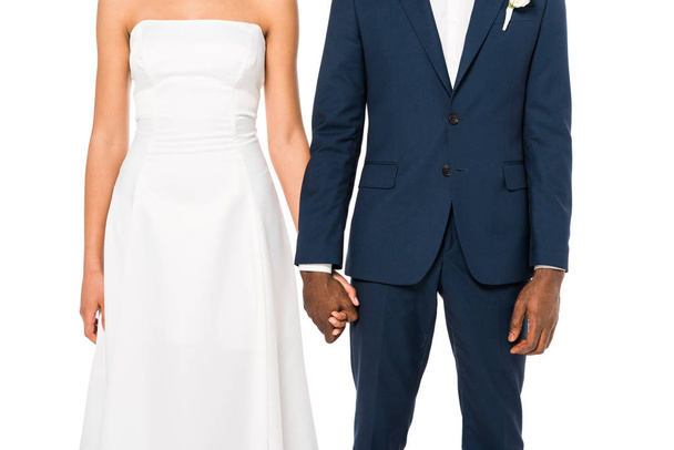 cropped view of african american bride and bridegroom holding hands while standing isolated on white  - Fotoğraf, Görsel