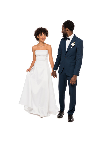 happy african american bridegroom holding hands with beautiful bride in wedding dress isolated on white  - Φωτογραφία, εικόνα
