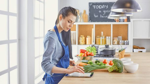 若い女性は、台所で食べ物を準備します。健康食品 - 野菜 - 写真・画像
