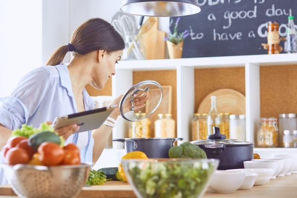 Image of a young pretty girl standing in the kitchen and is coo - Photo, Image