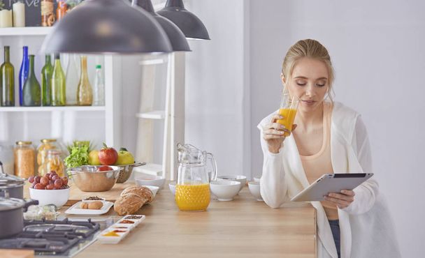 beautiful young woman using a digital tablet in the kitchen - Foto, afbeelding