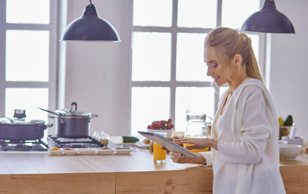 bella giovane donna utilizzando un tablet digitale in cucina - Foto, immagini