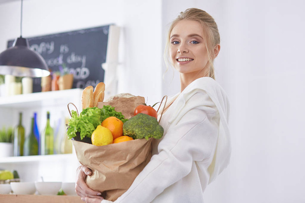 Nuori nainen tilalla ruokakauppa laukku vihanneksia Standi
 - Valokuva, kuva