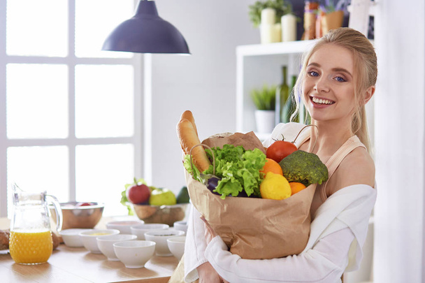 Giovane donna che tiene borsa della spesa con verdure Standi
 - Foto, immagini
