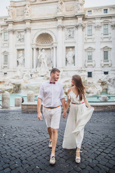 young beautiful couple in white clothes stands near Trevi Fountain in Rome in Italy - Zdjęcie, obraz