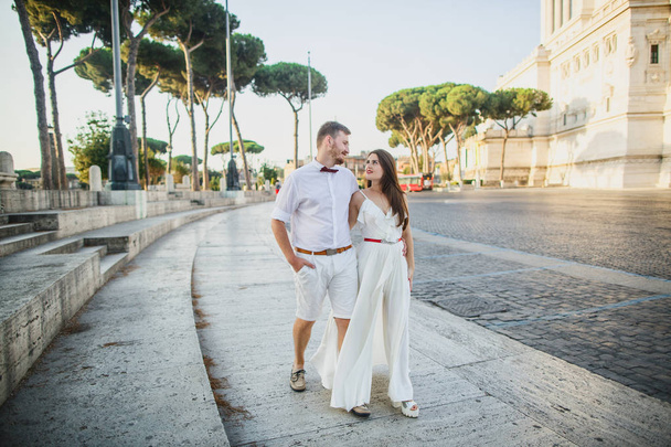young beautiful couple in white clothes walks in Rome in Italy at sunset - Foto, imagen