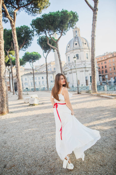 young beautiful girl in white clothes walks in Rome in Italy at sunset - Фото, зображення