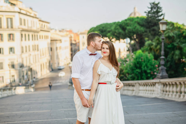 young beautiful couple in white clothes walks in Rome in Italy at sunset - Φωτογραφία, εικόνα