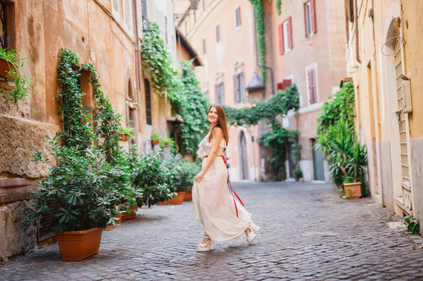 young beautiful girl in white clothes walks in Rome in Italy at sunset - Фото, изображение