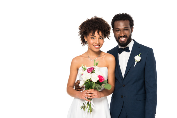 happy curly african american bride smiling while holding bouquet near bridegroom isolated on white  - Photo, Image