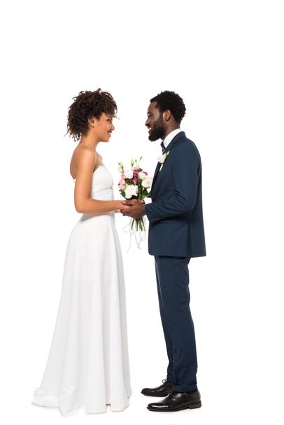 felice sposa africana americana tenendo bouquet vicino allo sposo isolato su bianco
  - Foto, immagini