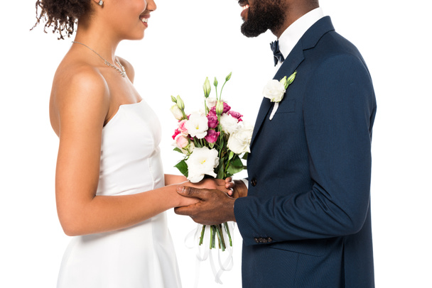 cropped view of happy african american bride and bridegroom holding bouquet isolated on white  - Photo, Image