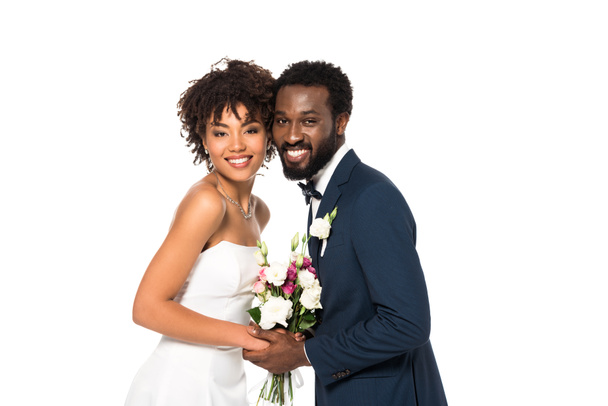 smiling african american bride and bridegroom holding bouquet isolated on white - 写真・画像