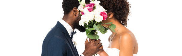panoráma lövés az afrikai-amerikai menyasszony és a vőlegény arcok, míg a gazdaság virágok elszigetelt fehér  - Fotó, kép