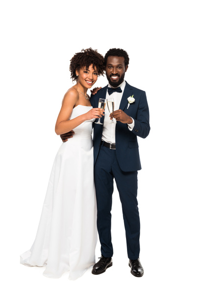 cheerful african american bride and bridegroom holding champagne glasses isolated on white  - Foto, Bild