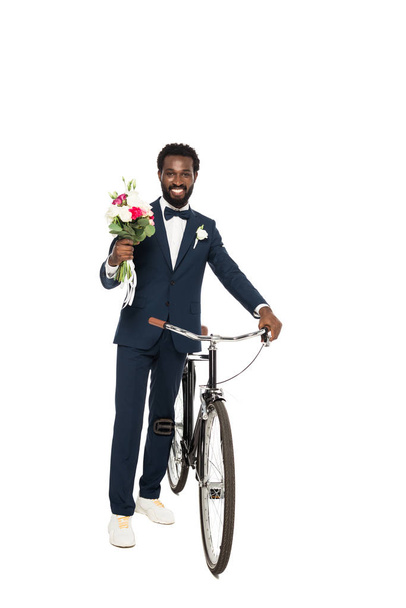handsome african american man holding bouquet and bicycle isolated on white  - Фото, зображення