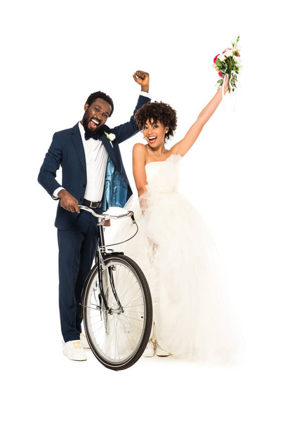 felice sposo africano americano gesticolando con la sposa mentre tiene la bicicletta isolata sul bianco
  - Foto, immagini