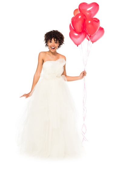 excited african american bride holding heart-shaped balloons while standing in wedding dress isolated on white  - Zdjęcie, obraz