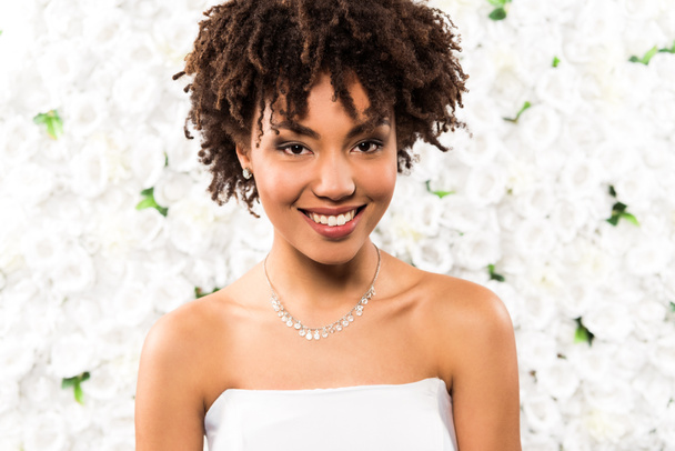 cheerful african american bride looking at camera near flowers  - Foto, imagen