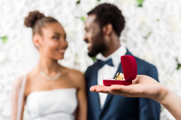 selective focus of man holding box with wedding ring near african american couple  - 写真・画像