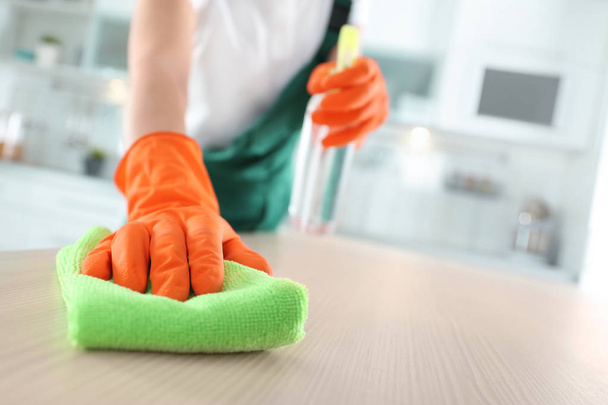 Werknemer in handschoenen schoonmaak tafel met Rag, close-up. Ruimte voor tekst - Foto, afbeelding