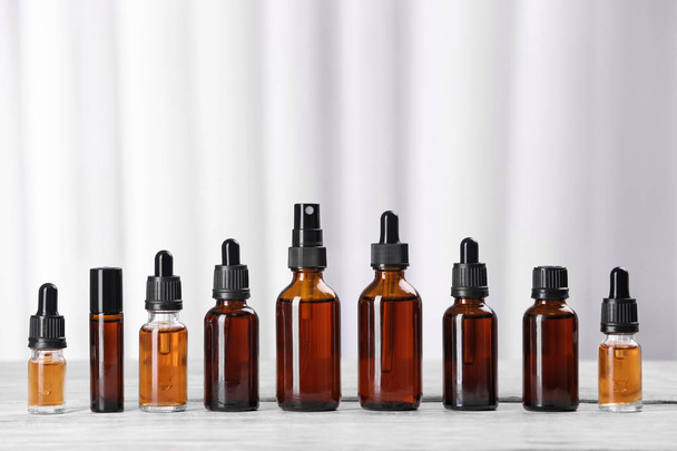 Bottles of essential oils on table against light background. Cosmetic products - Фото, зображення