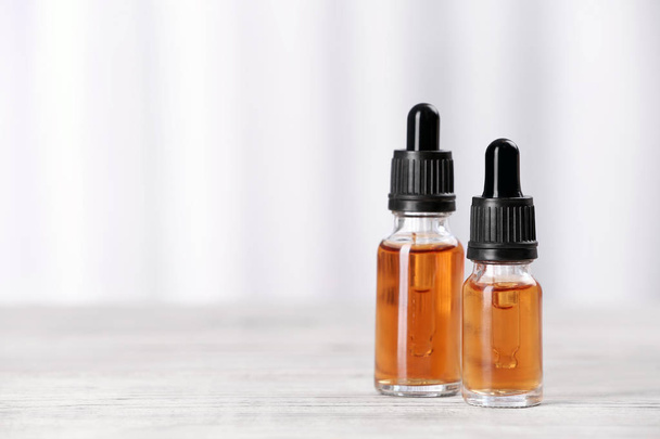 Bottles of essential oils on table against light background, space for text. Cosmetic products - Φωτογραφία, εικόνα