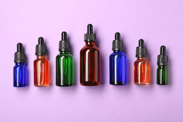 Bottles of essential oils on color background, flat lay. Cosmetic products - Foto, immagini