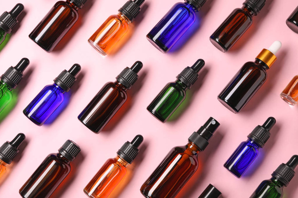 Bottles of essential oils on color background, flat lay. Cosmetic products - Фото, зображення