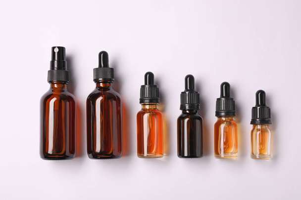 Bottles of essential oils on light background, top view. Cosmetic products - Photo, Image