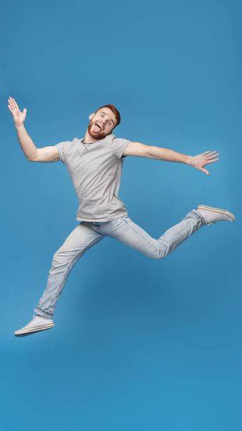 Divertido millennial chico saltando en el aire y engañando
 - Foto, imagen