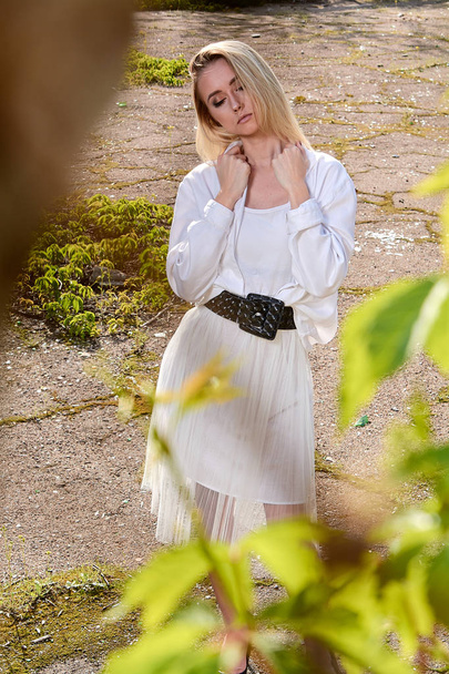 Blond kobieta w starym słonecznym letnim parku miejskim. Młoda kobieta nowoczesny portret. - Zdjęcie, obraz